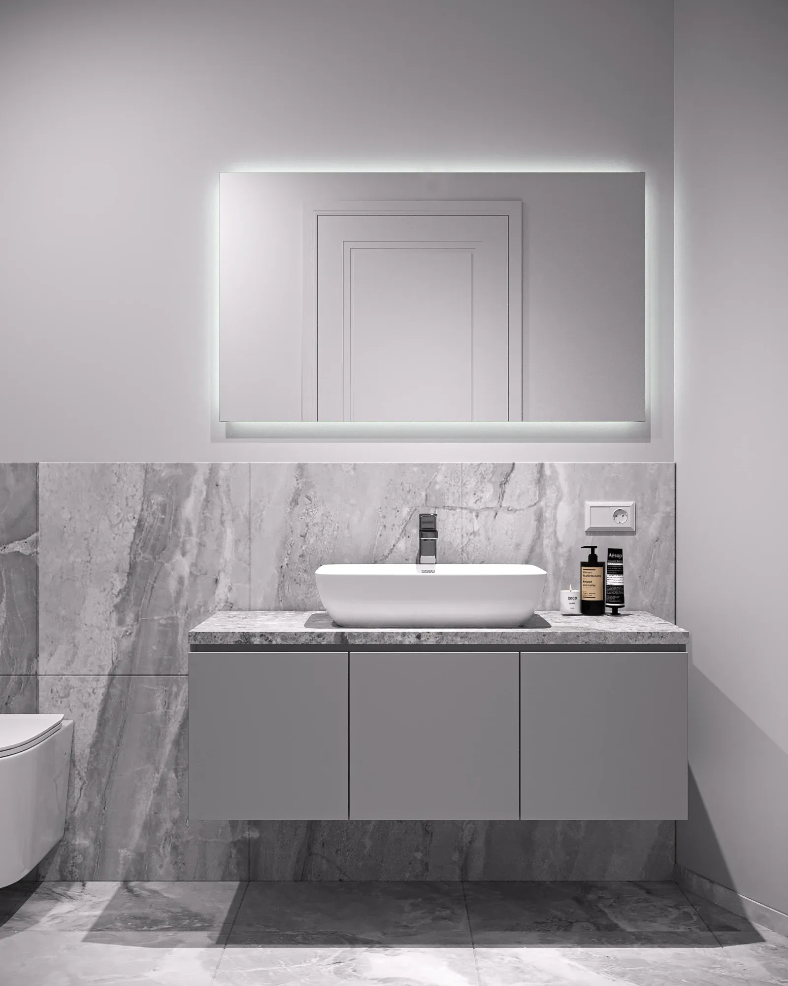 Guest bathroom in pale honed stone with a backlit rectangular mirror, white counter-top basin and a three-door vanity.